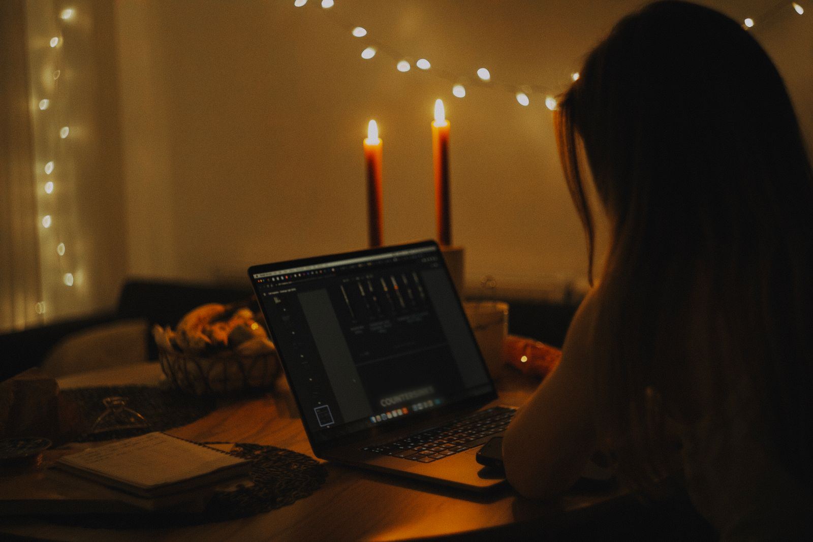 Person working on a laptop by candlelight during a power outage