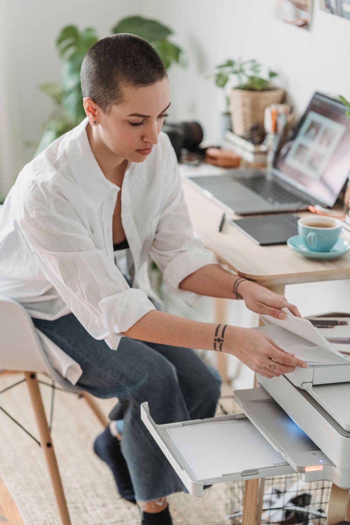 Person using a printer in a home office next to a laptop