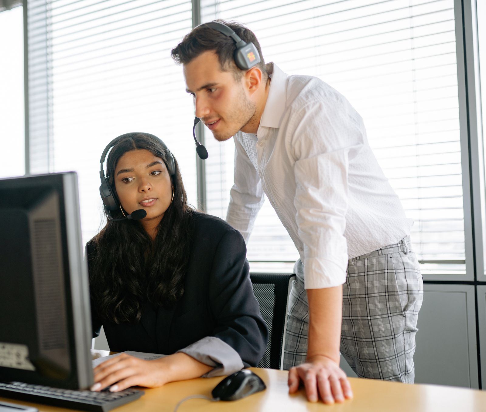IT support specialist helping a colleague at her computer